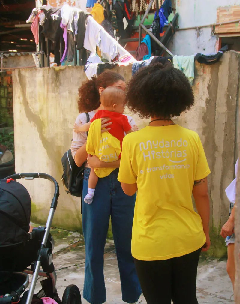 Voluntária conversa com moradores durante uma visita na comunidade